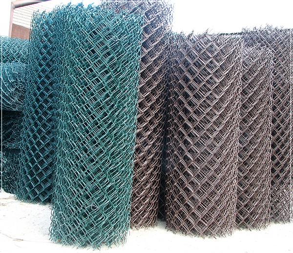 Siatka ogrodzeniowa zwinięta w rolki, zielona i ocynkowana, ułożona obok siebie.