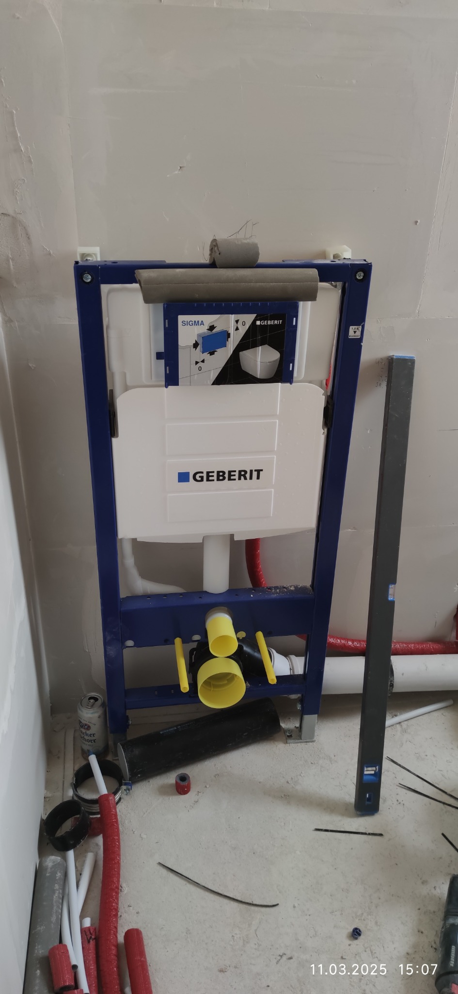 Stelaż podtynkowy Geberit Sigma z widocznymi rurami i elementami instalacji hydraulicznej w surowym wnętrzu, gotowy do zabudowy.