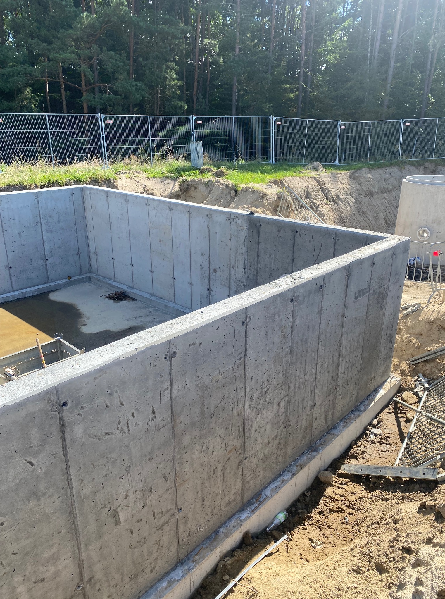 Świeżo wylane betonowe fundamenty domu jednorodzinnego, widok z góry, z zewnątrz. Na dnie woda.