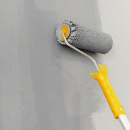 Dr Myjka - Szary wałek z żółtą rączką maluje ścianę na szaro. Widoczne świeże pociągnięcia farby i struktura wałka. Oświetlenie naturalne, skupienie na detalu narzędzia i efekt malowania.