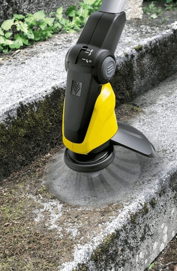 Szczotka do czyszczenia powierzchni usuwa mech z kamiennych schodów. Widoczne drobne zanieczyszczenia i resztki po czyszczeniu. Narzędzie czarno-żółte.