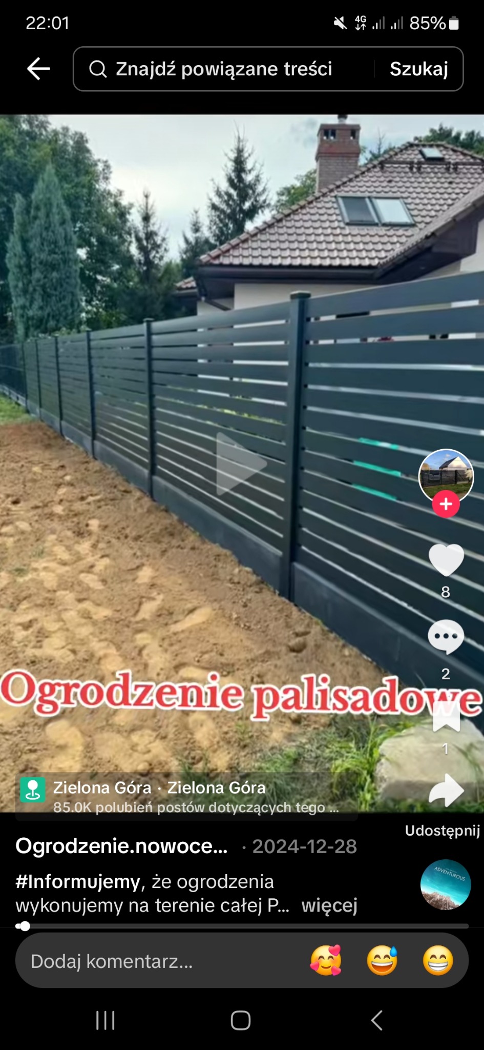 Nowoczesne, poziome ogrodzenie palisadowe w kolorze antracytowym,  z widocznym fragmentem domu w tle. Minimalistyczny design, regularny układ.