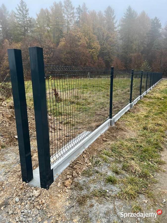 Ciemne panele ogrodzeniowe z podmurówką betonową na tle drzew w Koszalinie. Widok z boku ukazuje precyzję montażu i estetyczne wykończenie.