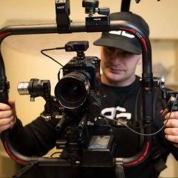 bartekgrzegorczyk.pl - Operator z Lublina obsługuje profesjonalny stabilizator kamery z zamontowanym aparatem i dodatkowym osprzętem, przygotowując się do nagrania ujęcia.