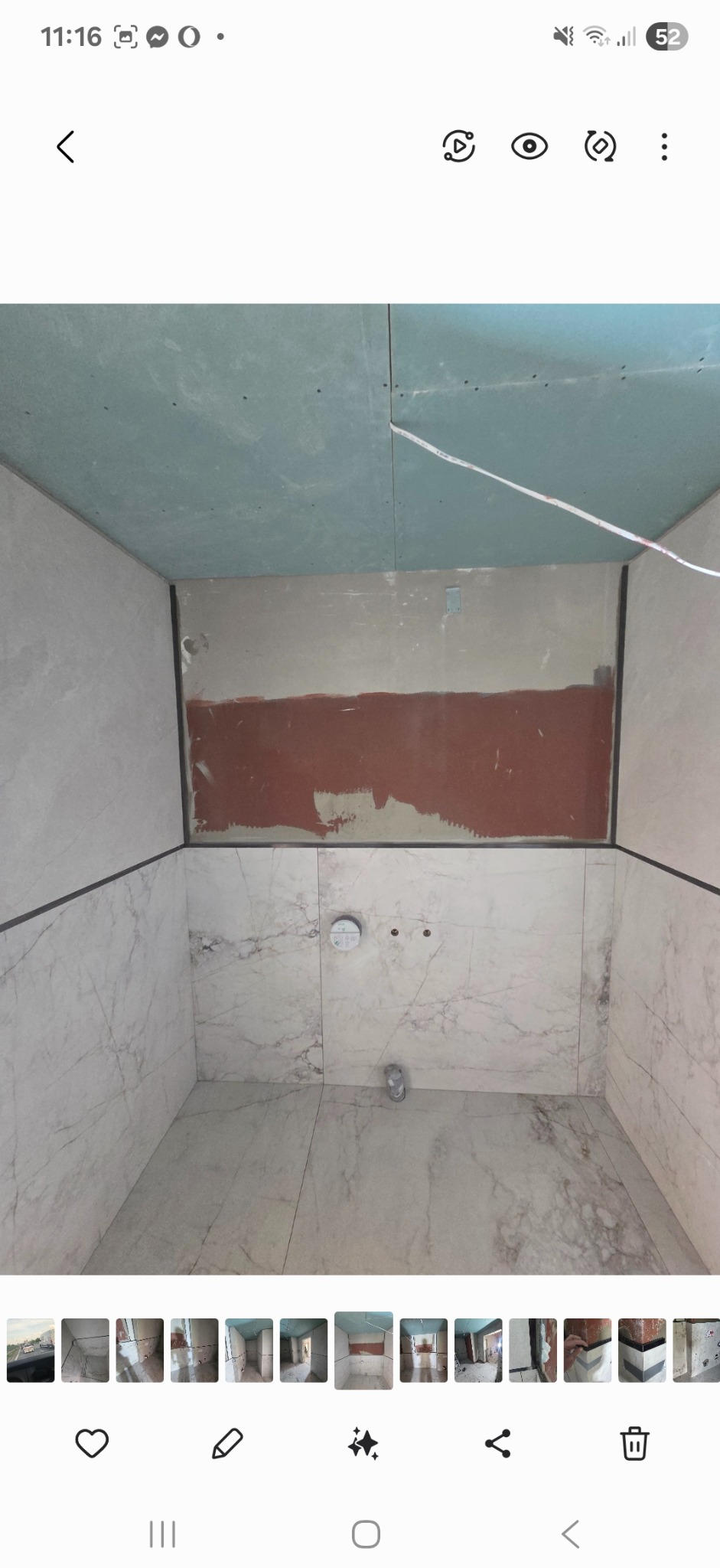 Wnętrze łazienki w trakcie prac wykończeniowych: częściowo położone marmurowe płytki, surowy sufit z płyt kartonowo-gipsowych, przygotowane miejsce na armaturę.