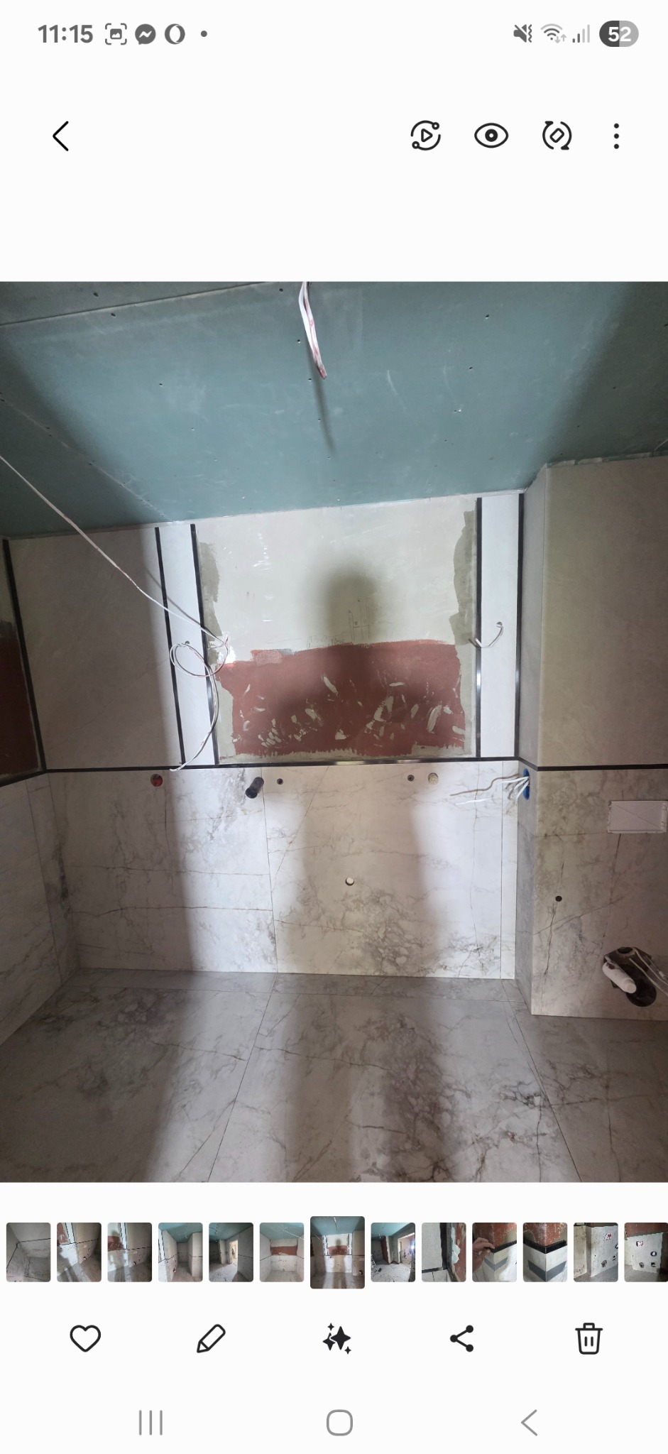 Łazienka w trakcie remontu: ściany i podłoga wyłożone marmurowymi płytkami, sufit z płyt kartonowo-gipsowych, widoczne przewody elektryczne i fragment ściany z resztkami kleju.