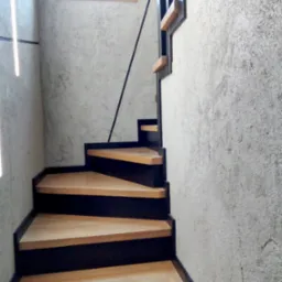 Nowoczesne schody z drewnianymi stopniami i czarną, metalową balustradą, na tle ściany o surowej fakturze. Ujęcie z dołu, widoczne okno w górnej części.