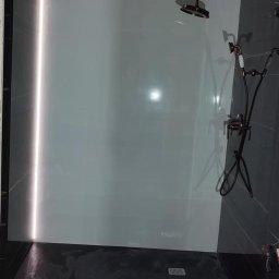 Projekt Wnętrz Sebastian Burski - Nowoczesna kabina prysznicowa z deszczownicą, czarno-białymi płytkami i podświetleniem LED. Widoczne kable elektryczne w suficie, sugerujące etap wykończenia.