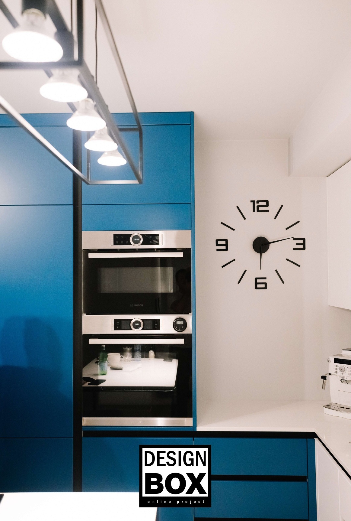 Niebieska zabudowa kuchenna z piekarnikiem Bosch i designerskim zegarem ściennym we Wrocławiu. Nowoczesna aranżacja wnętrza.