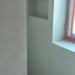 Pracownia Usługowa Agata Binkowska - Szara ściana z fakturą, w tle wnęka i fragment okna. Minimalistyczne wykończenie wnętrza, neutralna kolorystyka, bliski kadr na strukturę ściany.