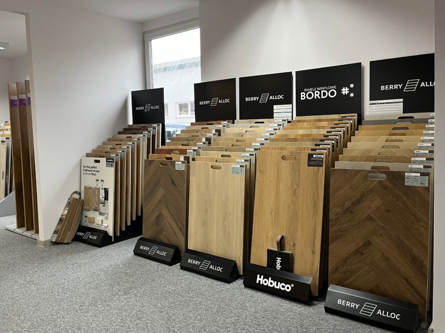 Ekspozycja paneli podłogowych Berry Alloc i Hobuco w sklepie: różne wzory i kolory, w tym jodełka. Prezentacja paneli winylowych Bordo.