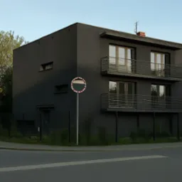 Dwukondygnacyjny, ciemnoszary dom z balkonami i płaskim dachem, widziany z rogu ulicy, obok znak drogowy. Nowoczesny design, minimalistyczna bryła, kontrast z zielenią.