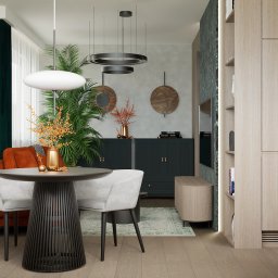 Twoje Nowe Studio Projektowe Ewa Kromska - Stylowe wnętrze: okrągły stół z krzesłami, pomarańczowa sofa, zabudowa kuchenna z piekarnikiem i rośliny doniczkowe. Dekoracyjne oświetlenie i marmurowe akcenty.