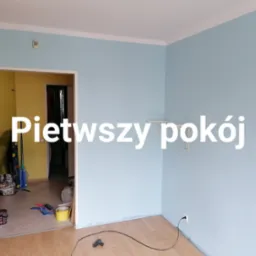 Błękitne ściany świeżo pomalowanego pokoju z drewnianą podłogą. Widoczne akcesoria malarskie w sąsiednim pokoju. Minimalistyczne wnętrze po odnowieniu.