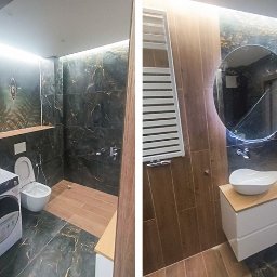 Arko - Nowoczesna łazienka z czarnymi płytkami imitującymi marmur, drewnianymi akcentami i okrągłym lustrem z podświetleniem LED. Widoczna pralka i grzejnik.