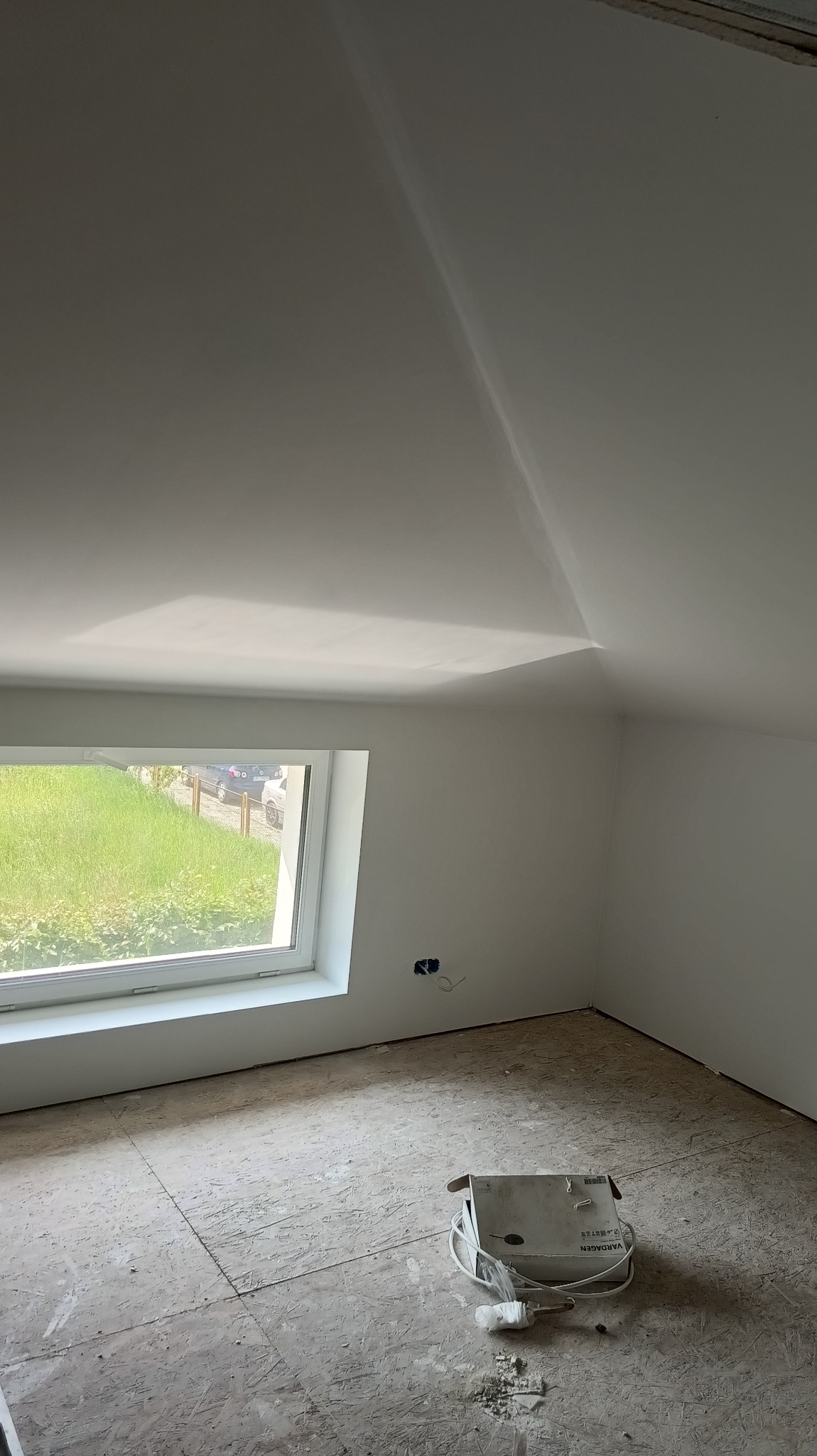 Gładkie, białe ściany i sufit po montażu płyt G-K w pokoju na poddaszu w Kędzierzynie-Koźlu. Widoczne okno i instalacja elektryczna.