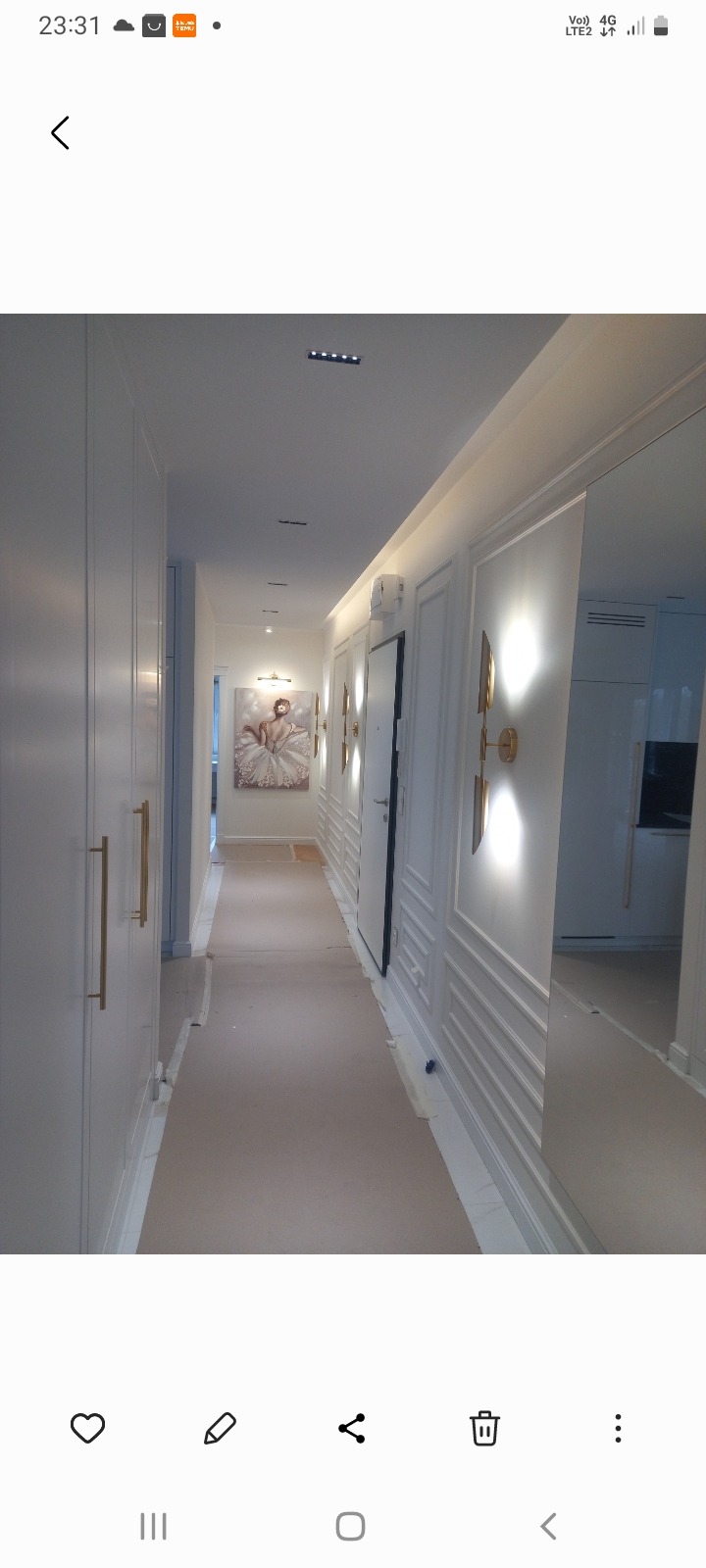 Biały korytarz z szafami w zabudowie, sztukaterią i złotymi lampami ściennymi. Na końcu korytarza widoczny obraz z baletnicą.