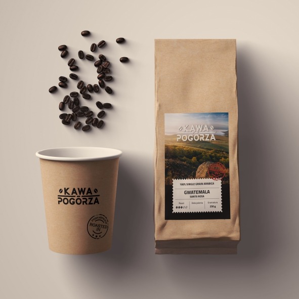 Kraftowa torba z kawą Gwatemala Santa Rosa i kubek z logo 'Kawa Pogórza' obok ziaren kawy. Minimalistyczna kompozycja z dbałością o detale.
