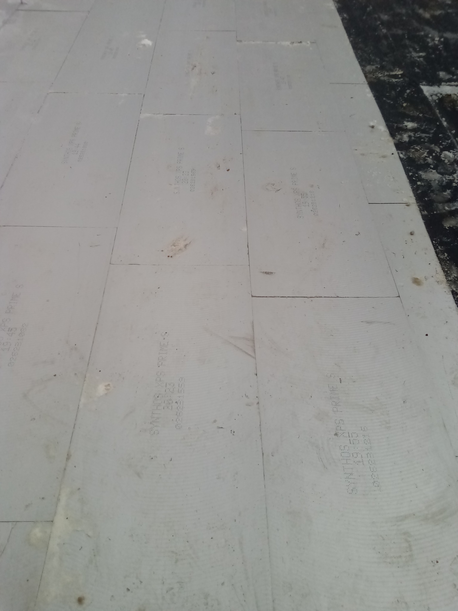 Ułożone płyty termoizolacyjne na dachu w Małdytach. Widoczne napisy 'SYNTHOS XPS PRIME S' na szarych płytach. Izolacja dachu przed dalszymi pracami.