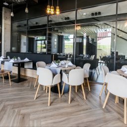 ZALENA GROUP SPÓŁKA Z OGRANICZONĄ ODPOWIEDZIALNOŚCIĄ - Jasna, drewnopodobna podłoga ułożona w jodełkę francuską w eleganckiej restauracji. Widoczne stoły z nakryciami i krzesła w neutralnych barwach.