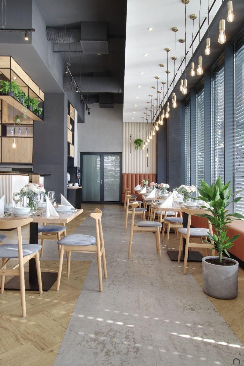 Elegancja restauracji: parkiet w jodełkę łączy się z betonową posadzką. Stoliki z kwiatami i oświetlenie tworzą wyjątkowy klimat wnętrza.