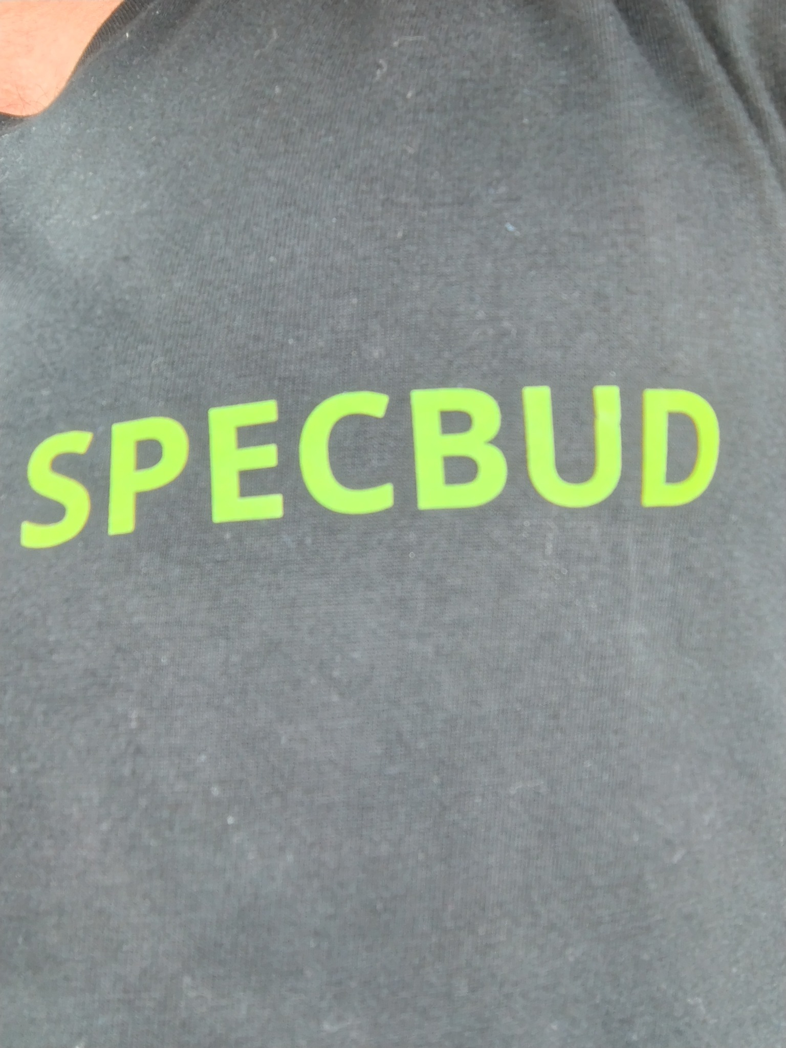Szara koszulka z jaskrawozielonym napisem 'SPECBUD' w centralnej części kadru, prezentująca logo firmy.