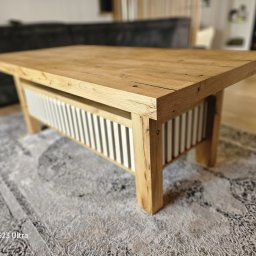 MPodłogi - Drewniany stolik kawowy z jasnego drewna, z białymi listwami pod blatem, ustawiony na wzorzystym dywanie w salonie. Widoczne naturalne słoje i detale wykończenia.