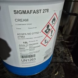 Libertad Robert Szydłowski - Puszka z dwuskładnikową farbą epoksydową Sigmafast 278 w kolorze kremowym, z widocznymi symbolami ostrzegawczymi i informacjami o produkcie.