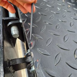 Libertad Robert Szydłowski - Czarny, metalowy podest z antypoślizgową fakturą, sprawdzany cienkim prętem przez dłoń. Widoczne elementy konstrukcyjne i mocowania.