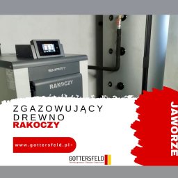 GOTTERSFELD SPÓŁKA Z OGRANICZONĄ ODPOWIEDZIALNOŚCIĄ - Nowoczesny piec zgazowujący drewno Rakoczy Smart z panelem sterowania i zbiornikiem, prezentowany w pomieszczeniu. Reklama firmy Gottersfeld.