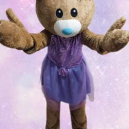 Pluszowy miś w fioletowej sukience i kokardą, kostium animatora na tle błyszczącego tła, z rozłożonymi rękami, zapraszający na imprezę.