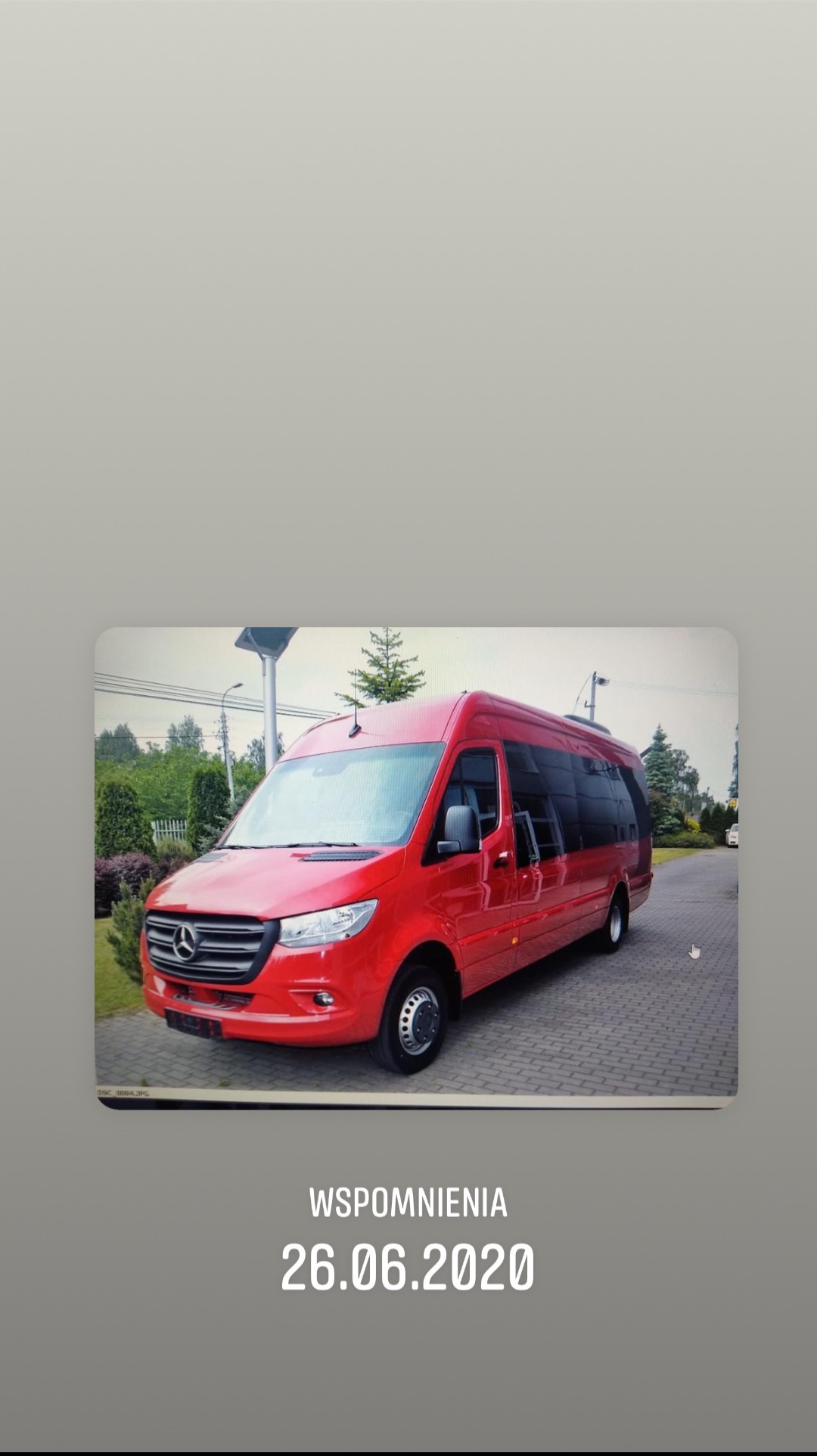 Czerwony bus Mercedes-Benz Sprinter z przyciemnianymi szybami, zaparkowany na kostce brukowej, w tle zieleń. Zdjęcie z datą 26.06.2020.
