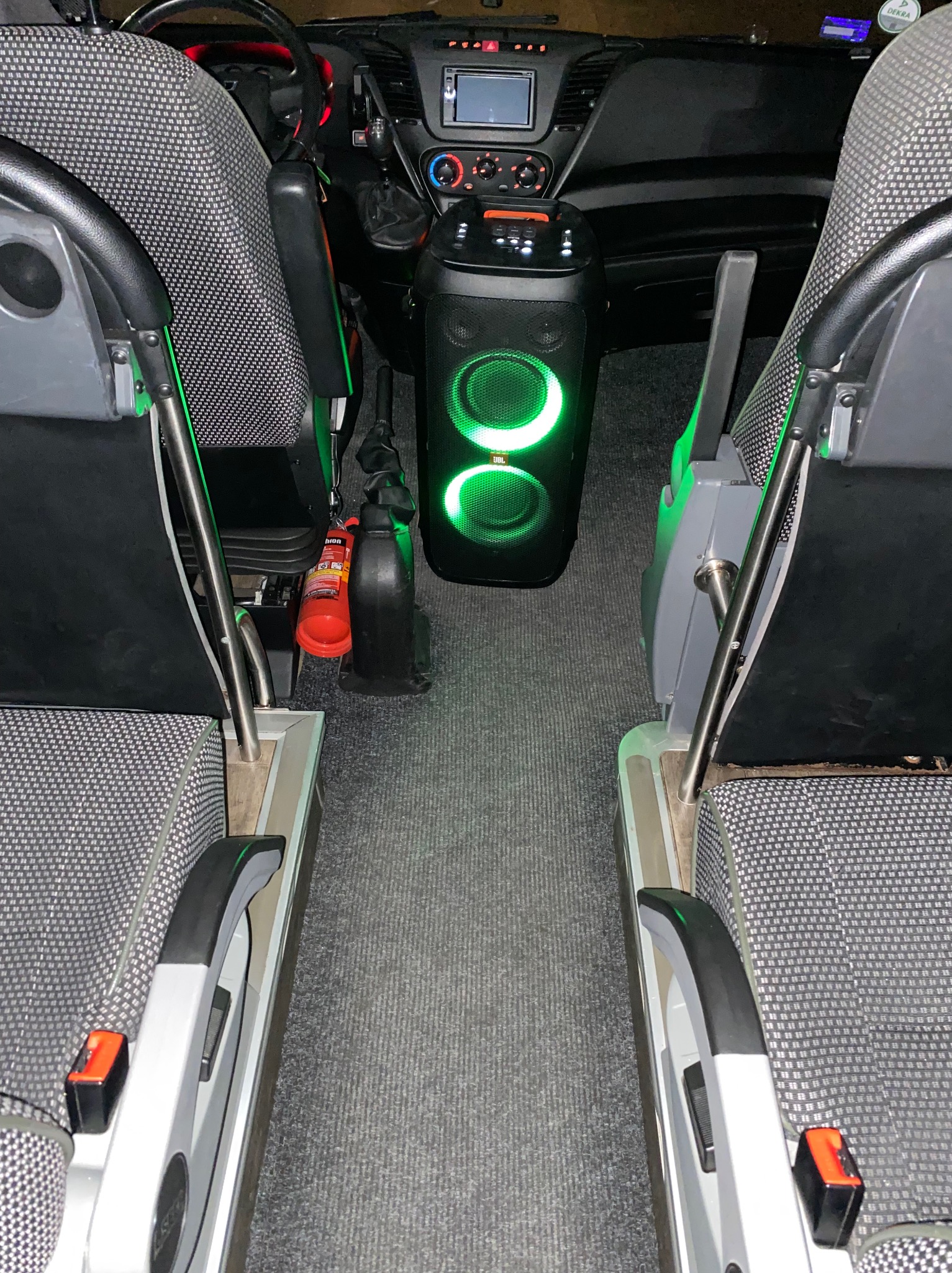 Wnętrze busa do przewozu osób w Dąbrowie Górniczej, z widocznym nagłośnieniem JBL z zielonym podświetleniem między fotelami pasażerskimi.