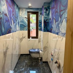 połączenie marmurowych płytek z artystyczną tapetą, czarny błyszczący gres na podłodze, nowoczesne wykończenie z dbałością o każdy detal.