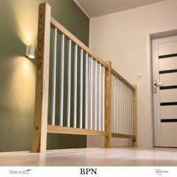 ZAB-DEKOR Arkadiusz Zabdyr - Drewniana balustrada z białymi, pionowymi elementami w korytarzu, oświetlona kinkietem. Widok z dołu, podkreślający detale i solidność wykonania.