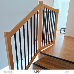 ZAB-DEKOR Arkadiusz Zabdyr - Nowoczesna balustrada schodowa z jasnego drewna i czarnych, pionowych elementów. Minimalistyczny design, widok z dołu schodów, jasne drewno podłogi.