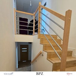 ZAB-DEKOR Arkadiusz Zabdyr - Jasne, drewniane schody z metalowymi elementami tworzącymi nowoczesną konstrukcję. Widoczne detale wykończenia i oświetlenie.