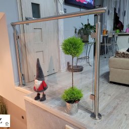 ZAB-DEKOR Arkadiusz Zabdyr - Nowoczesna balustrada szklana ze stali nierdzewnej, zabezpieczająca schody. W tle widoczny wystrój wnętrza domu z dekoracjami i meblami.