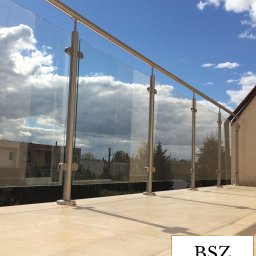 ZAB-DEKOR Arkadiusz Zabdyr - Szklana balustrada balkonowa z metalowymi słupkami, widok na błękitne niebo z chmurami. Jasna, beżowa posadzka balkonowa. Detal architektoniczny.