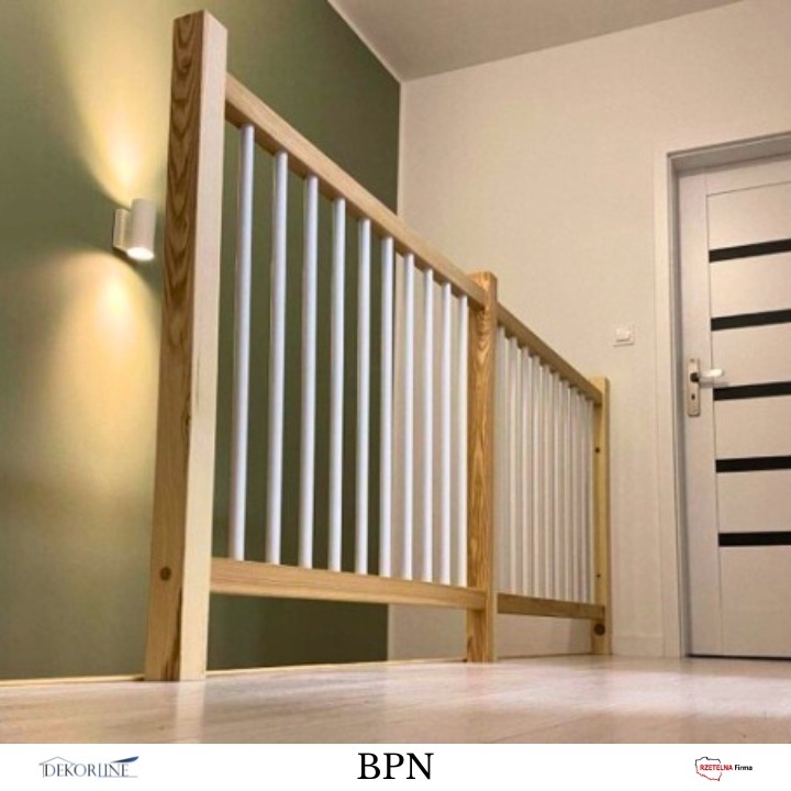 Drewniana balustrada z białymi, pionowymi elementami w korytarzu, oświetlona kinkietem. Widok z dołu, podkreślający detale i solidność wykonania.