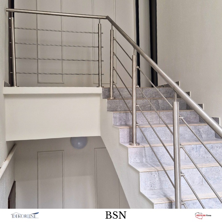 Metalowa barierka schodowa z poziomymi prętami, szare płytki na schodach, białe ściany z panelami. Minimalistyczny design.