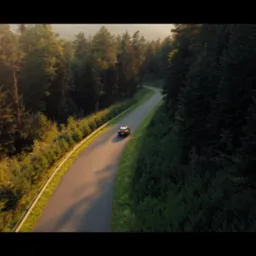 Samoch&oacute;d na krętej drodze otoczonej lasem, uchwycony z lotu ptaka w ciepłym, zachodzącym słońcu, tworzącym dramatyczne cienie i podkreślającym naturalne piękno krajobrazu.