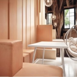 Arteriors - Jasne wnętrze z wiszącym fotelem i geometrycznymi meblami w odcieniach beżu i brązu. Nowoczesny design z akcentami drewna i naturalnego światła.