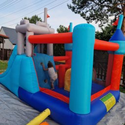 Fabryka Uśmiechu i Mebli David Parma - Kolorowy dmuchany zamek z tunelem i zjeżdżalnią w Gorzyczkach, z dzieckiem wspinającym się po ściance. Widoczny wentylator do pompowania.