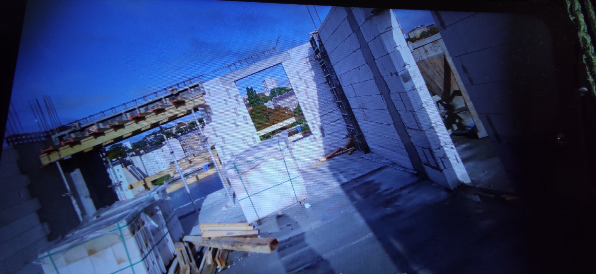 Wznoszenie ścian z betonu komórkowego na budowie. Widoczne zbrojenia i szalunki. W tle zabudowa miejska. Kąt ujęcia z góry.