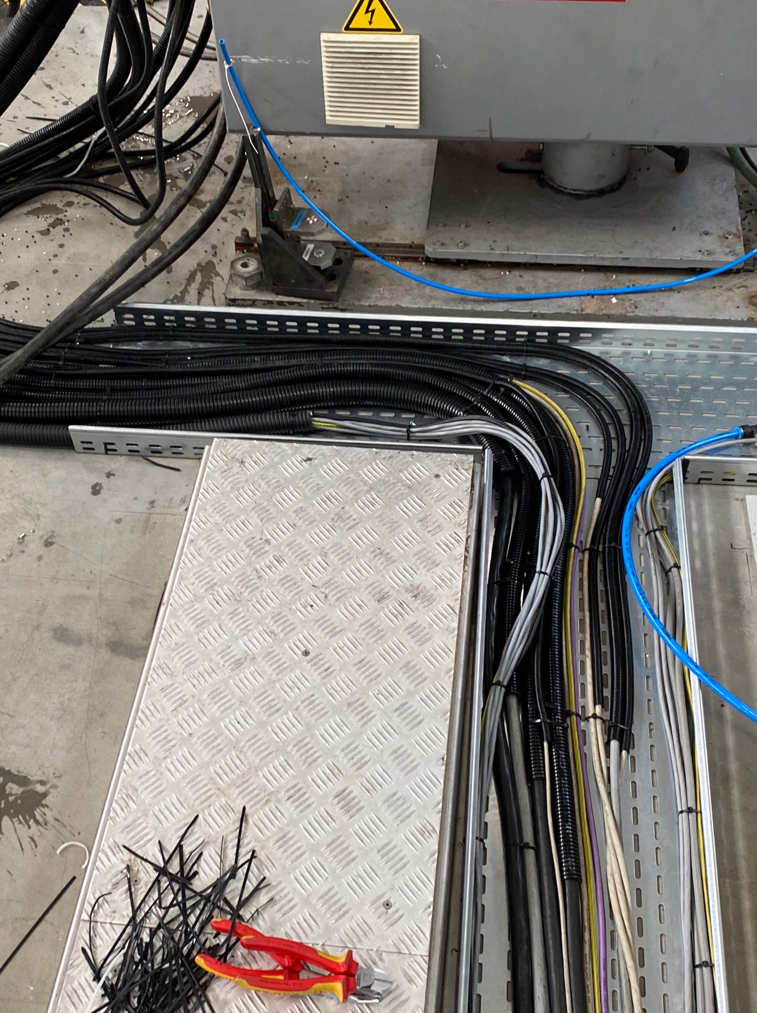 Ułożone kable w korytkach instalacyjnych z narzędziami i wiązkami kablowymi, widoczne przewody w różnych kolorach i średnicach.