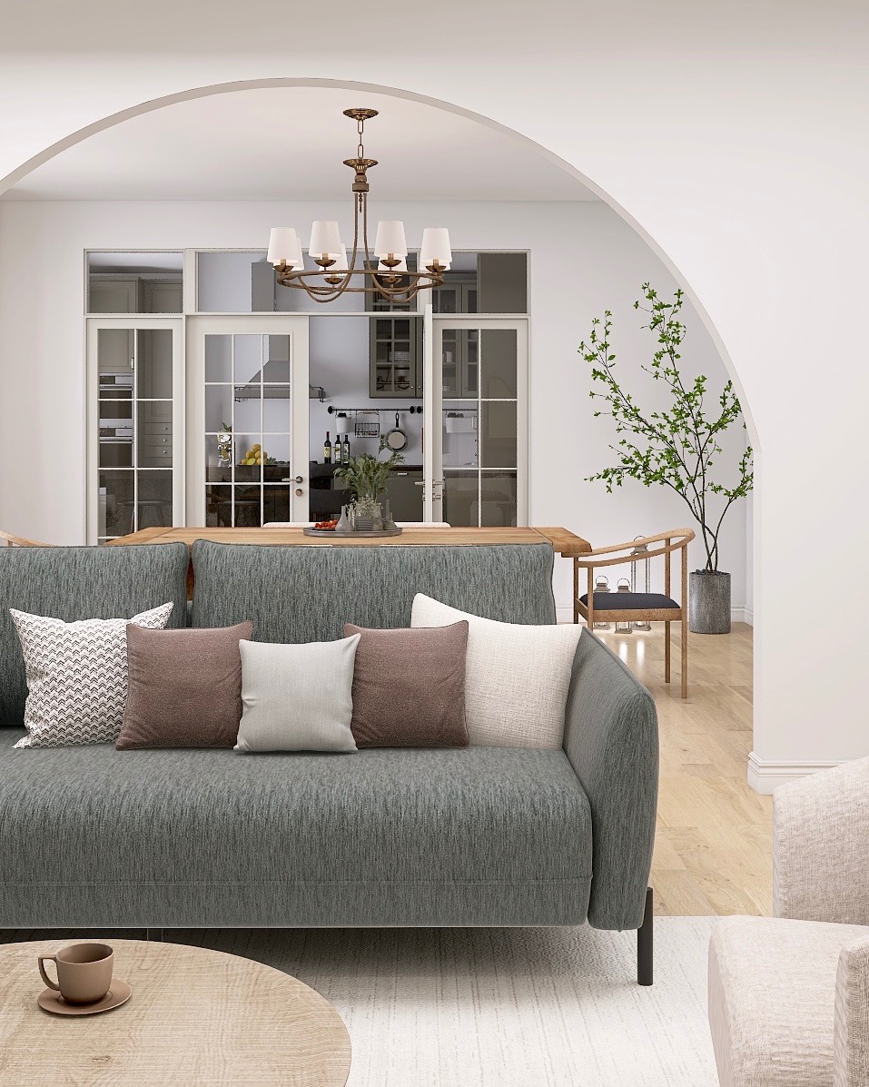 Jasne, przestronne wnętrze z szarą sofą, drewnianym stołem i widokiem na kuchnię przez szerokie, łukowate przejście. Minimalistyczny design z rośliną w rogu.