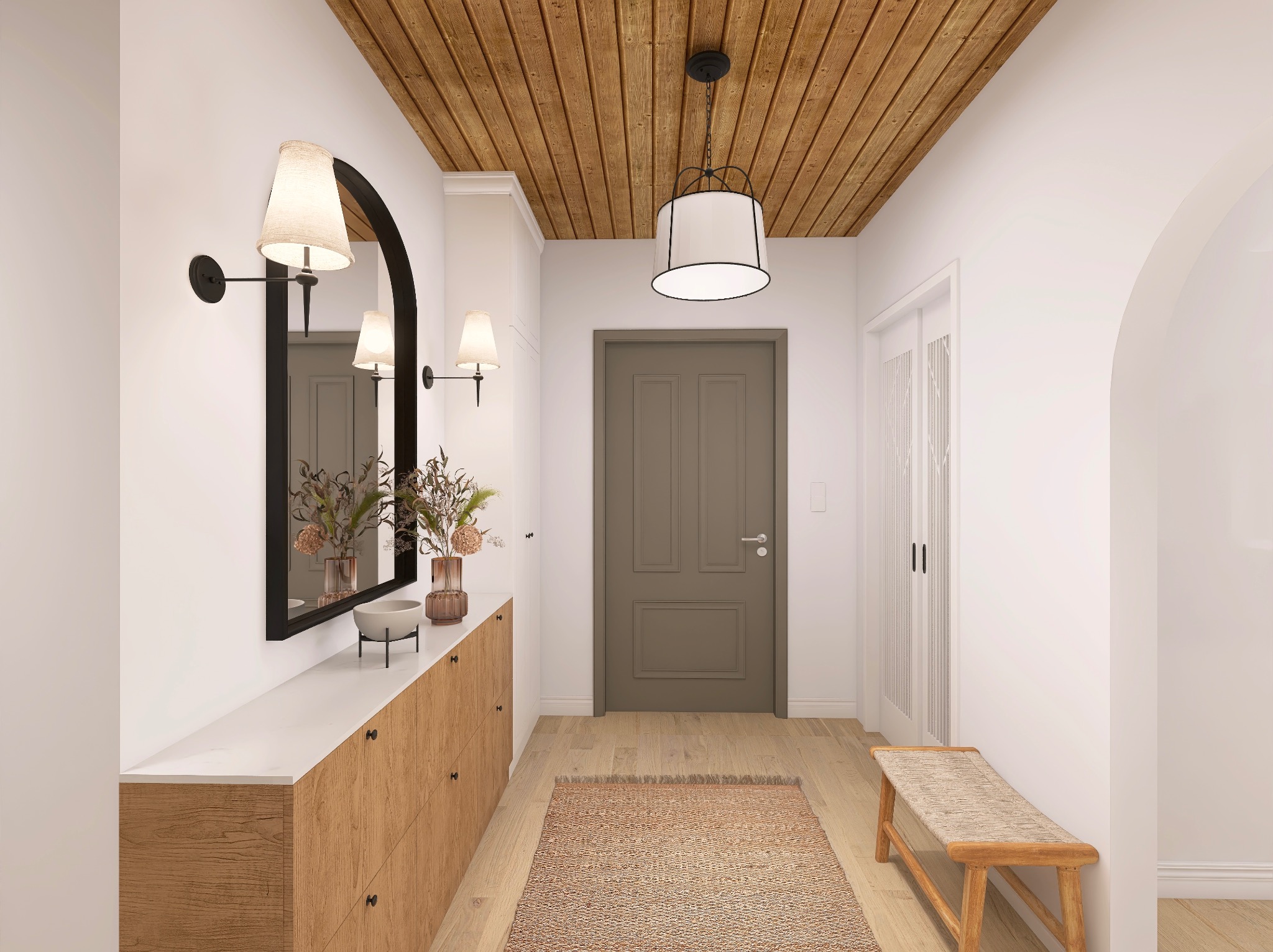 Jasny hol z drewnianym sufitem, lustrem w czarnej ramie i komodą. Na komodzie wazony z kwiatami i miska. Na podłodze dywanik i drewniana ławka.