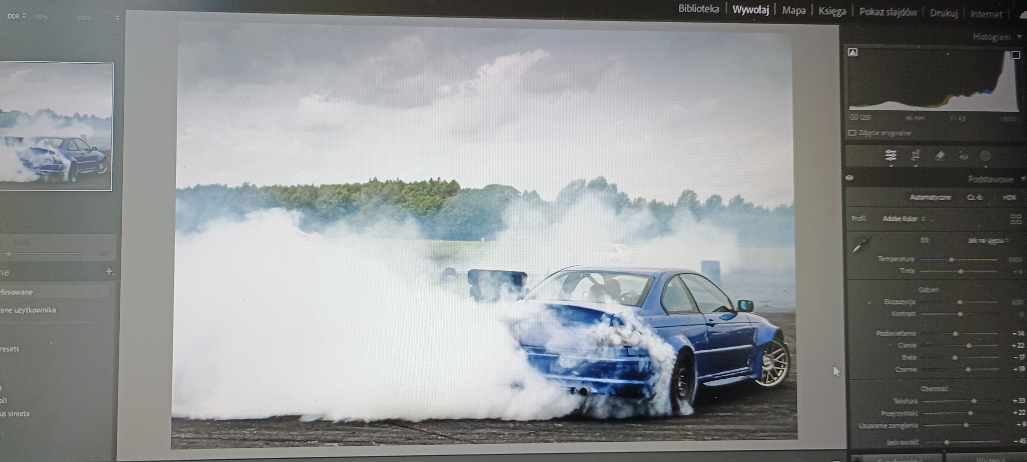 Niebieskie BMW E46 w intensywnym dymie podczas driftu, uchwycone w programie do edycji zdjęć. Widoczne ustawienia ekspozycji i histogram.