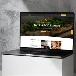 Aleksandra Godlewska Papaja Studio - Laptop prezentuje stronę internetową pizzerii 'Pod Kłosem' z Suwałk. Widoczny nagłówek z pizzą i menu, a także sekcja 'O nas' z zdjęciem osoby i pizzy.